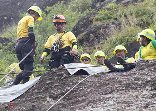 Équipe des Comandos avec casques et cordes pendant un sauvetage sur un versant rocheux.