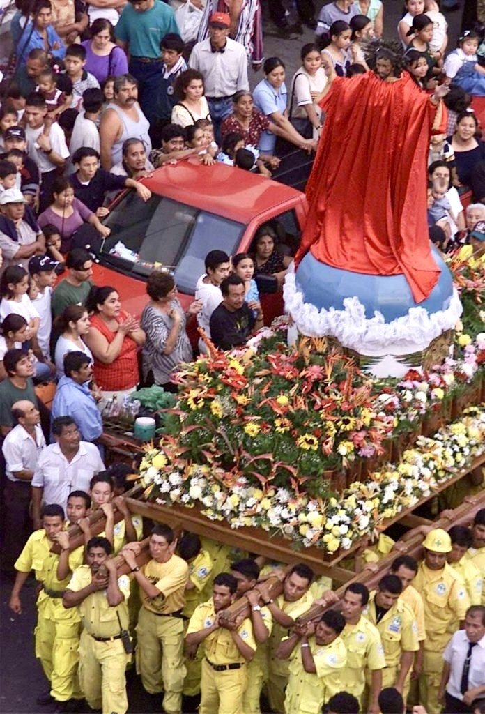 Des Comandos portent sur leurs épaules le brancard de procession avec la statue du Divino Salvador del Mundo au milieu de la foule.